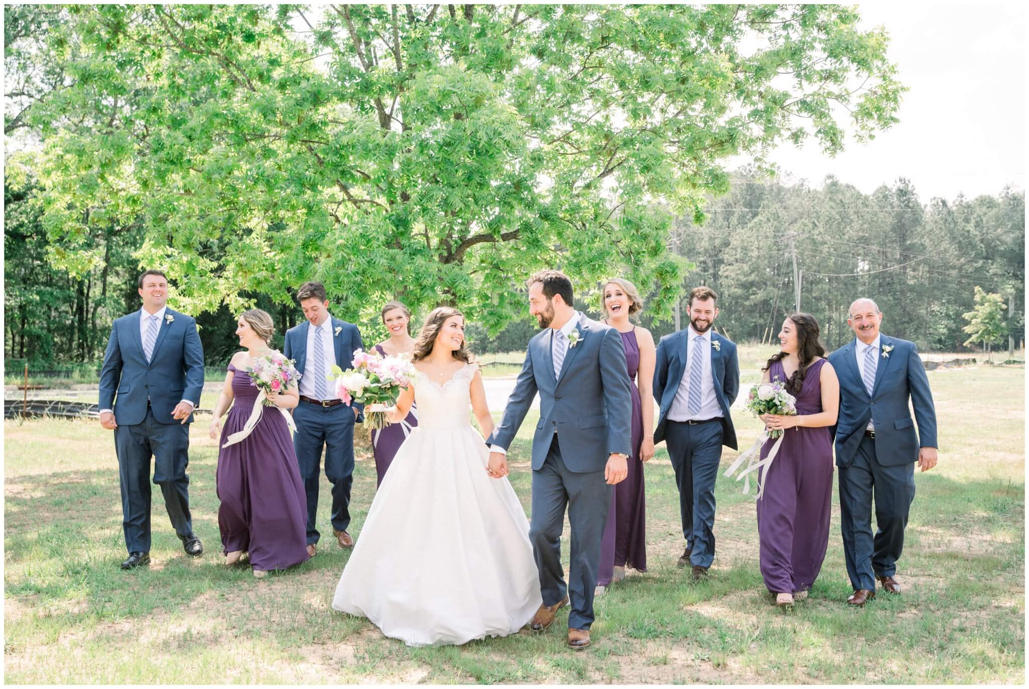 wedding party walking with newlyweds laughing