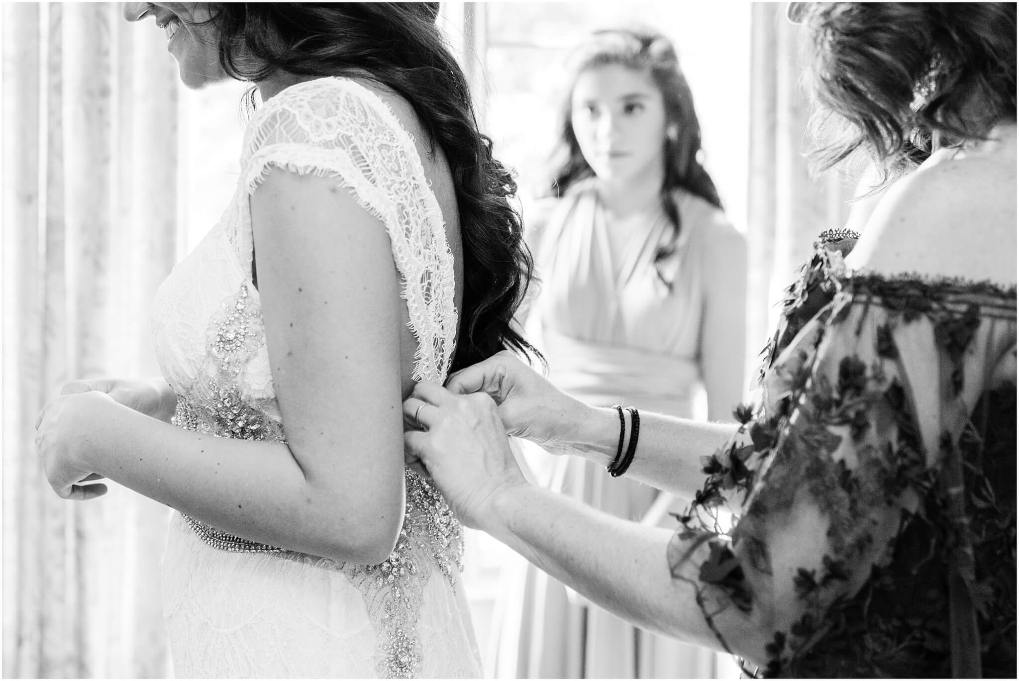 Mom helping brides get ready, sister looking on