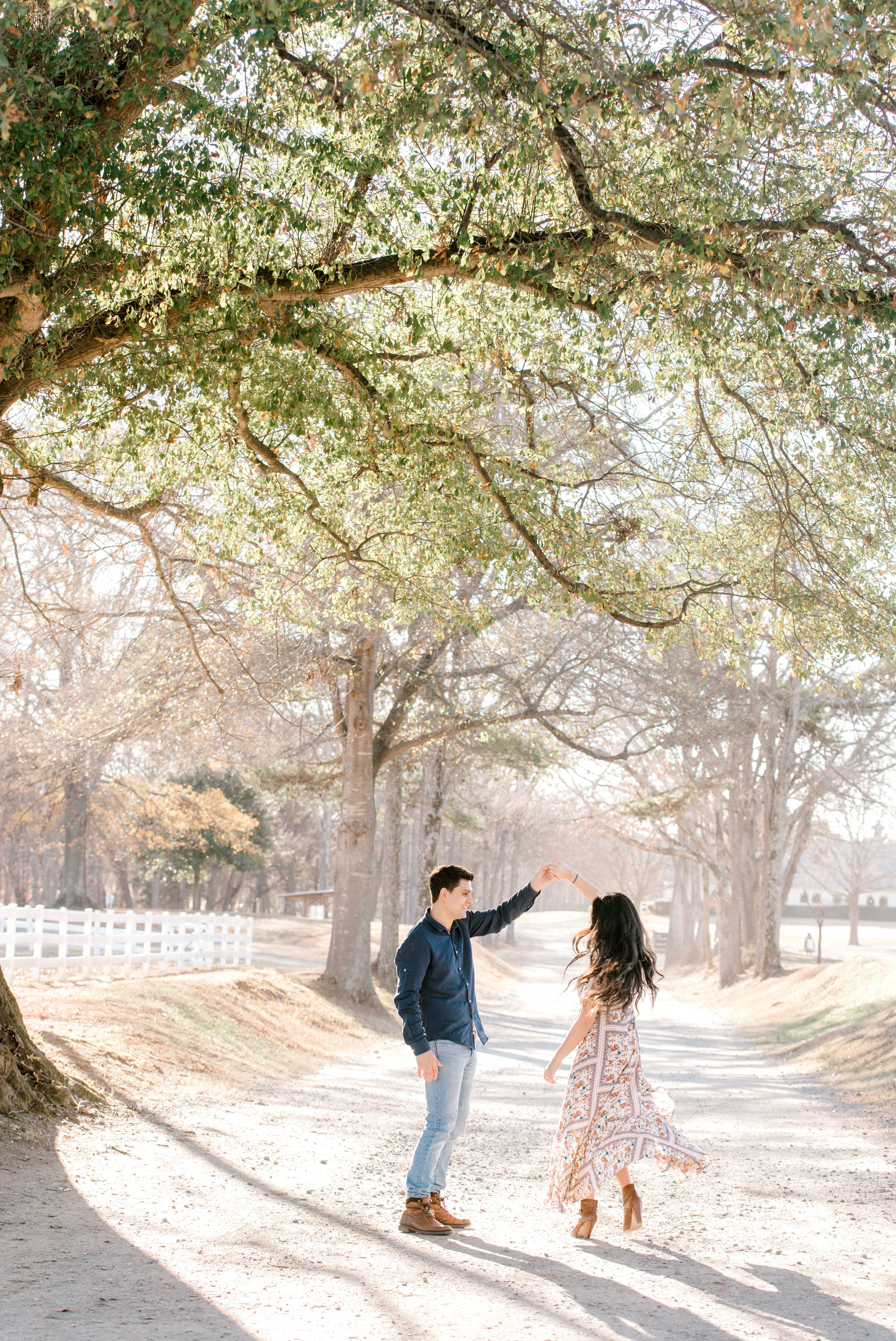couple twirling in sunlight engagement session at anne springs close greenway