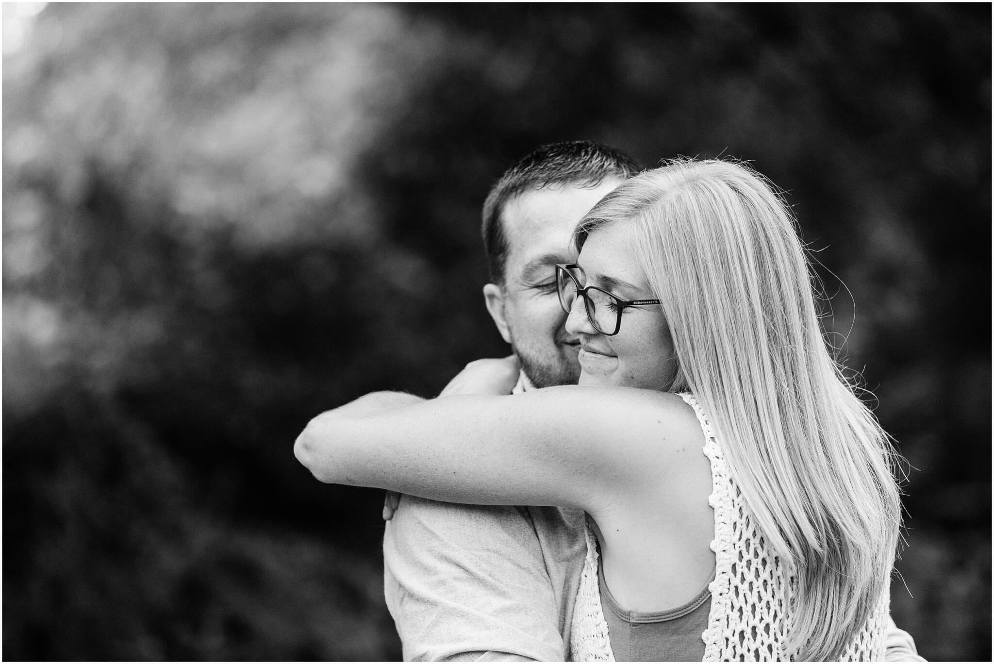 black and white photo kara and nathan hugging eachother in a wooded background