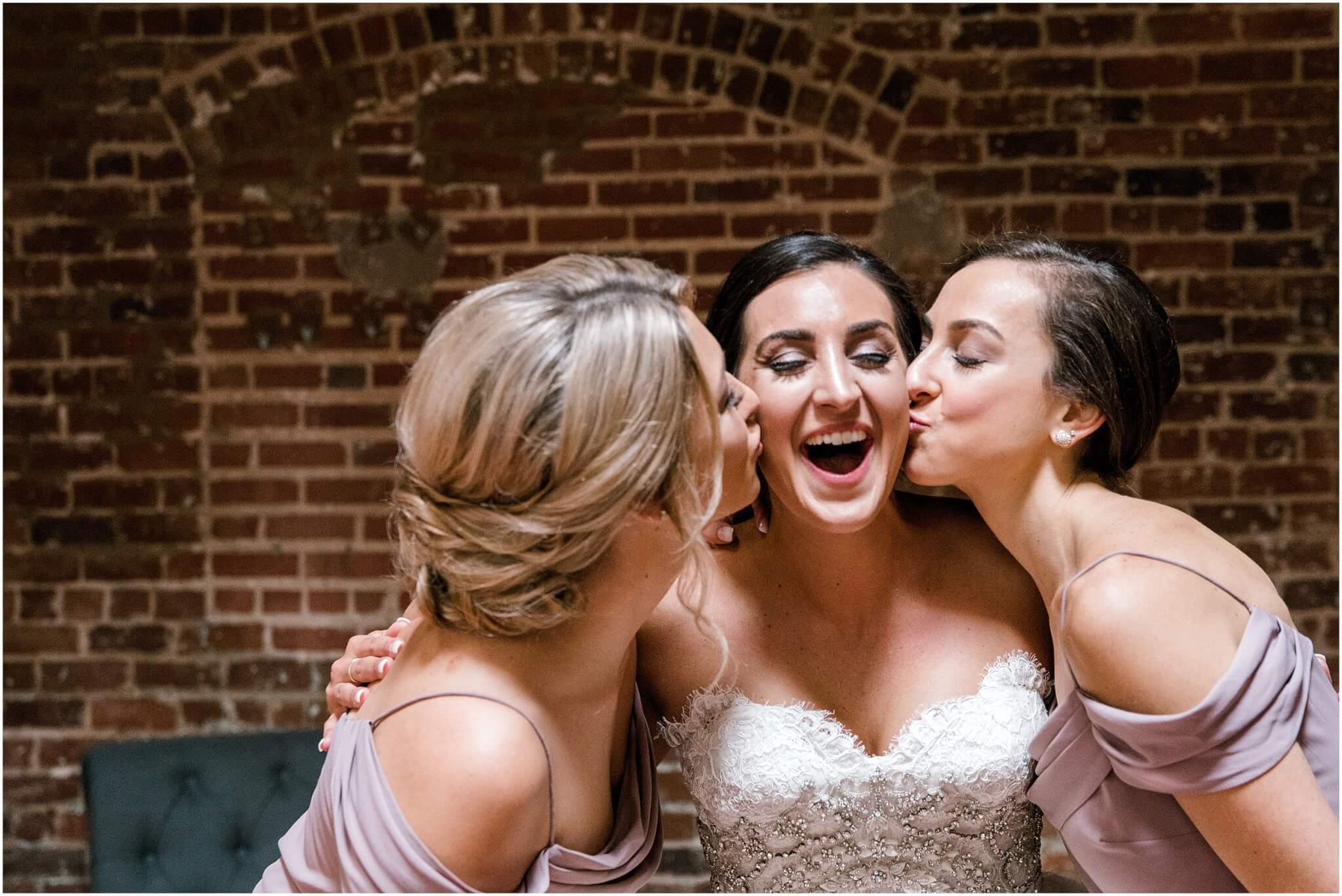 bride with bridesmaids kissing cheek before wedding