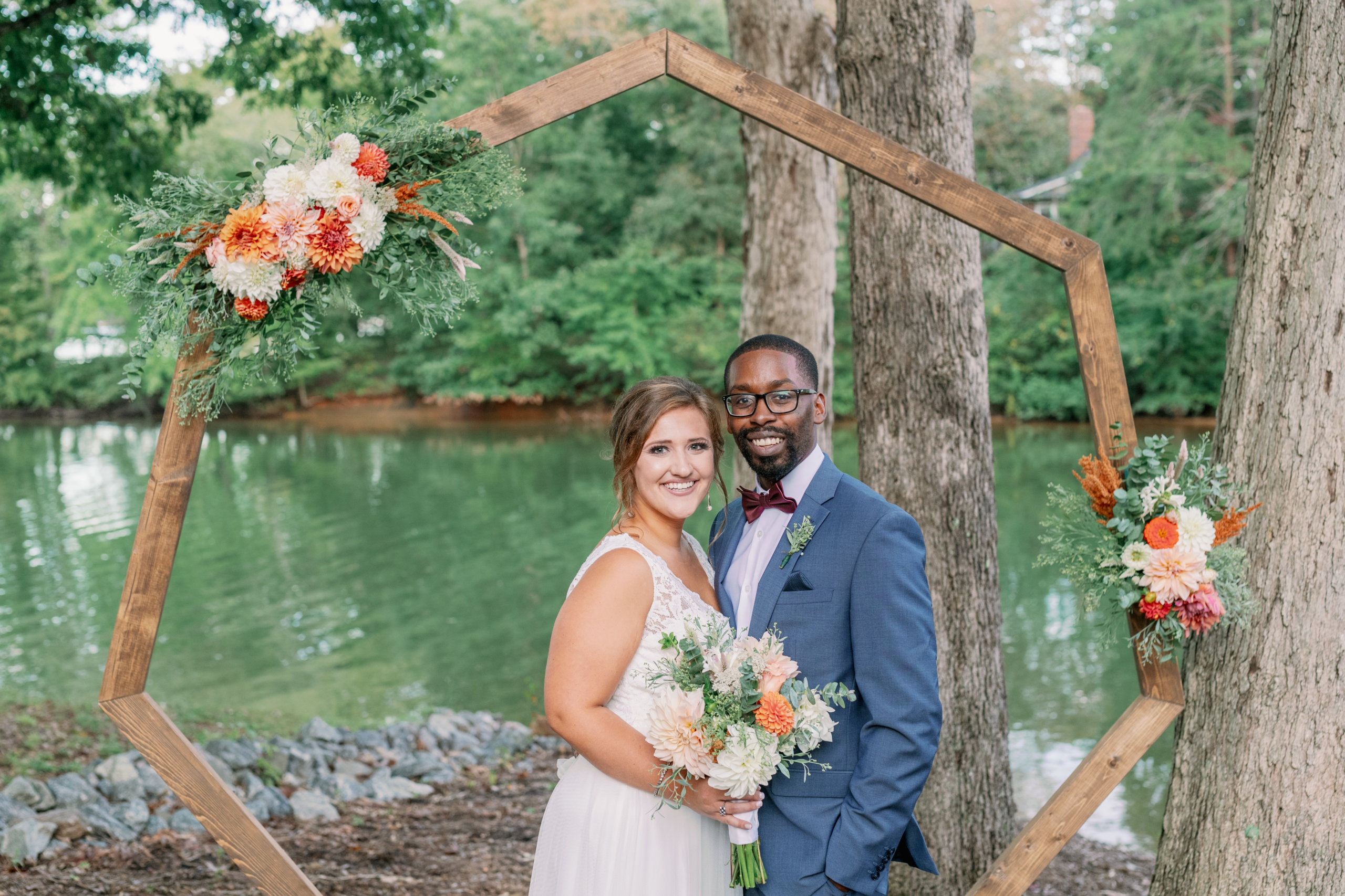 Bride and groom smiling in front of wedding arch