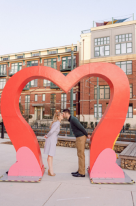 Couple kissing under heart sculpture