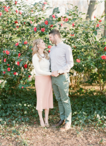 Couple holding hand and smiling in front of rose bush