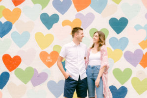 Couple smiling with multi-colored heart backdrop