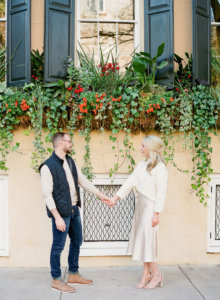 Couple holding hands in front of wall with plants