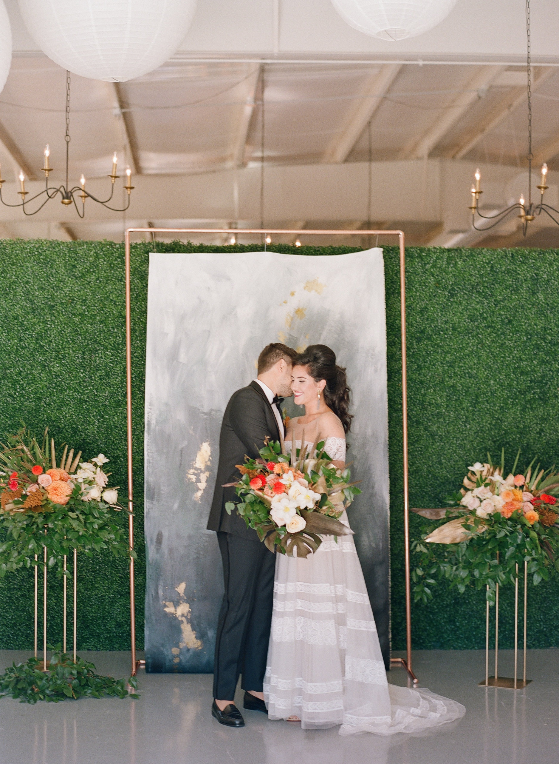 Bride and groom smiling in front of ceremony backdrop