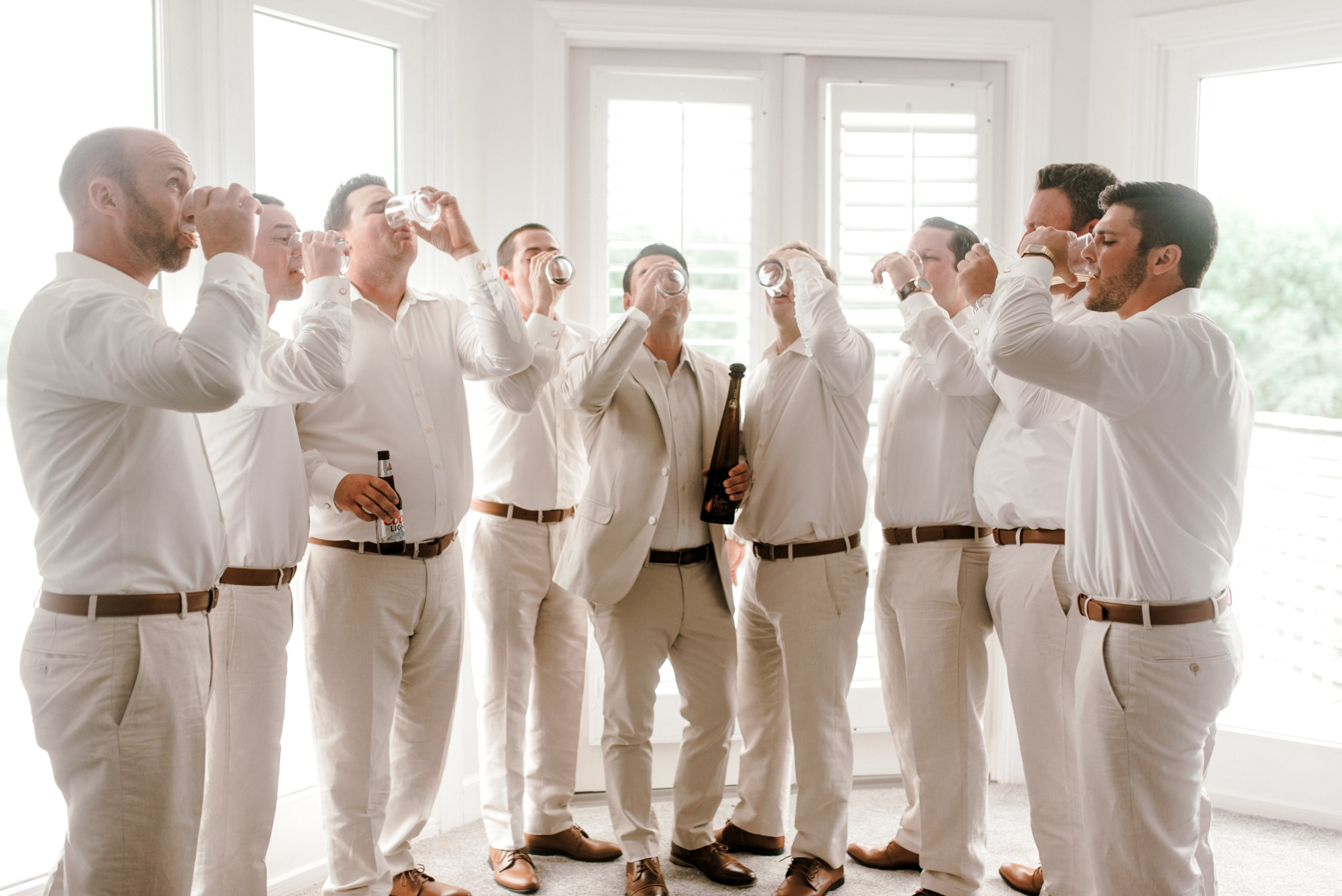 Groom and groomsmen sharing a drink before wedding day