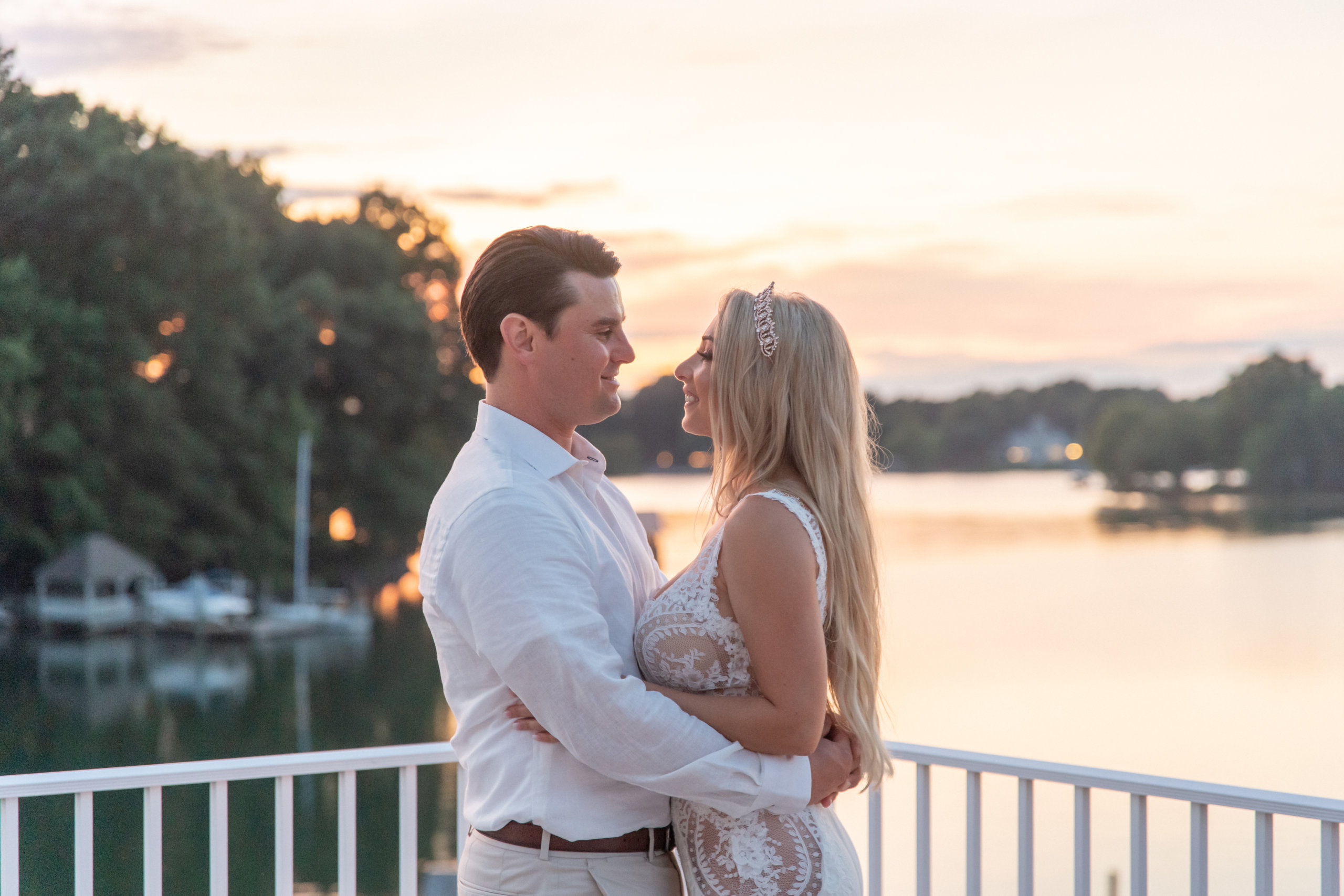 Bride and groom on dock in front of lake at sunset