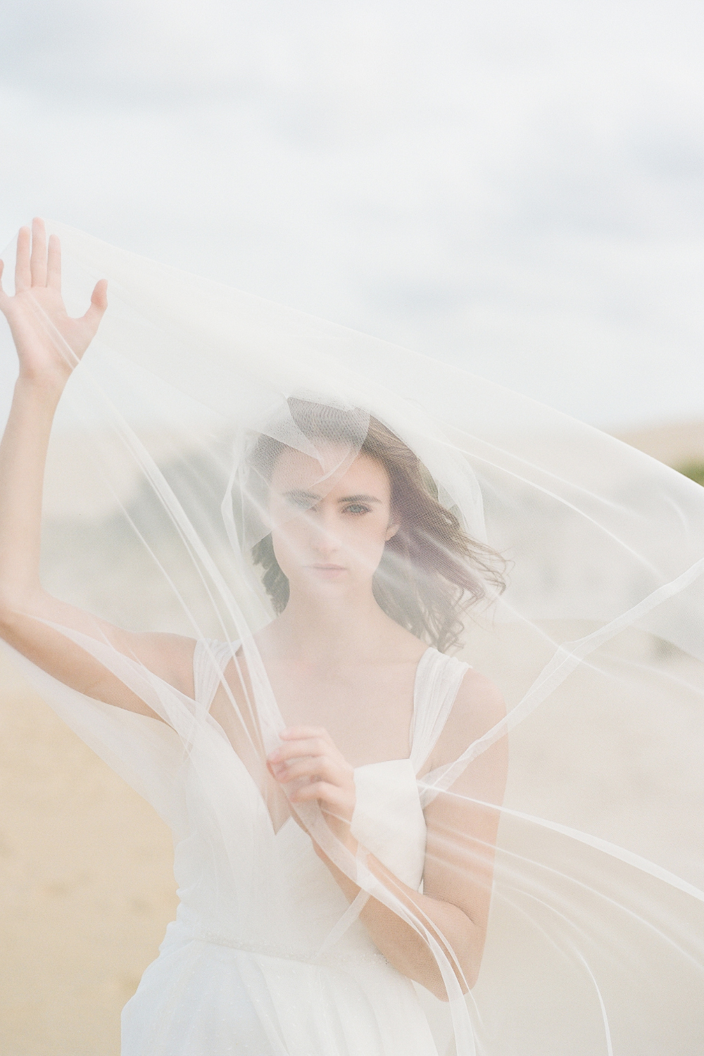 Bride at beach wedding with veil in front of face