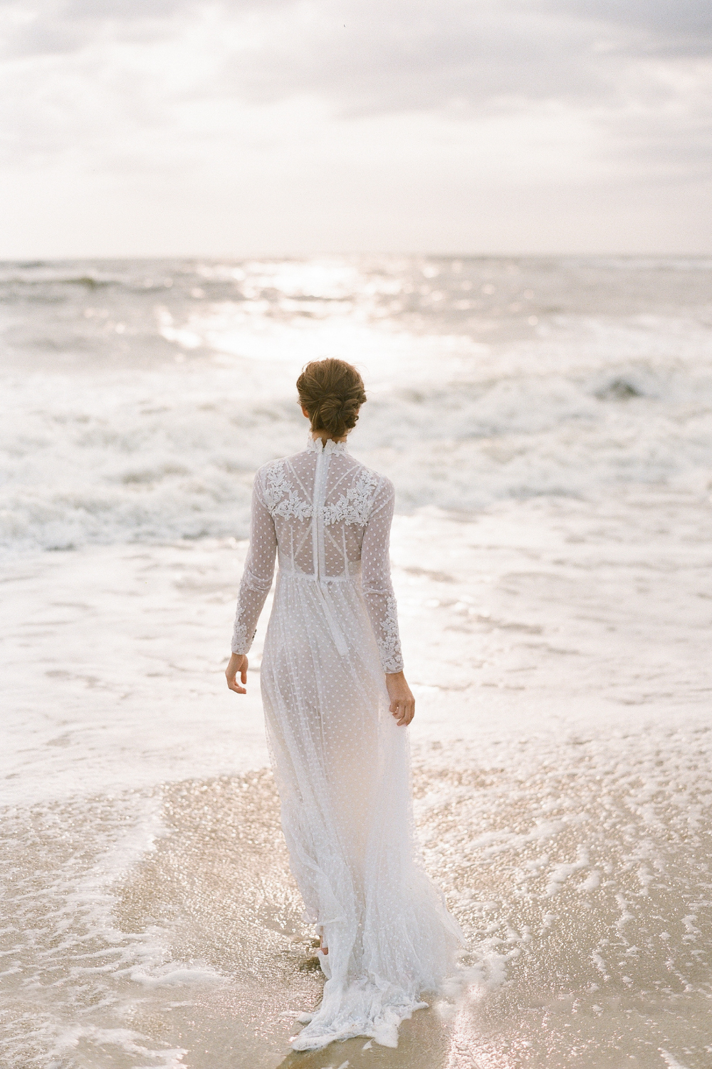 Bride walking towards ocean in vintage style beach wedding dress