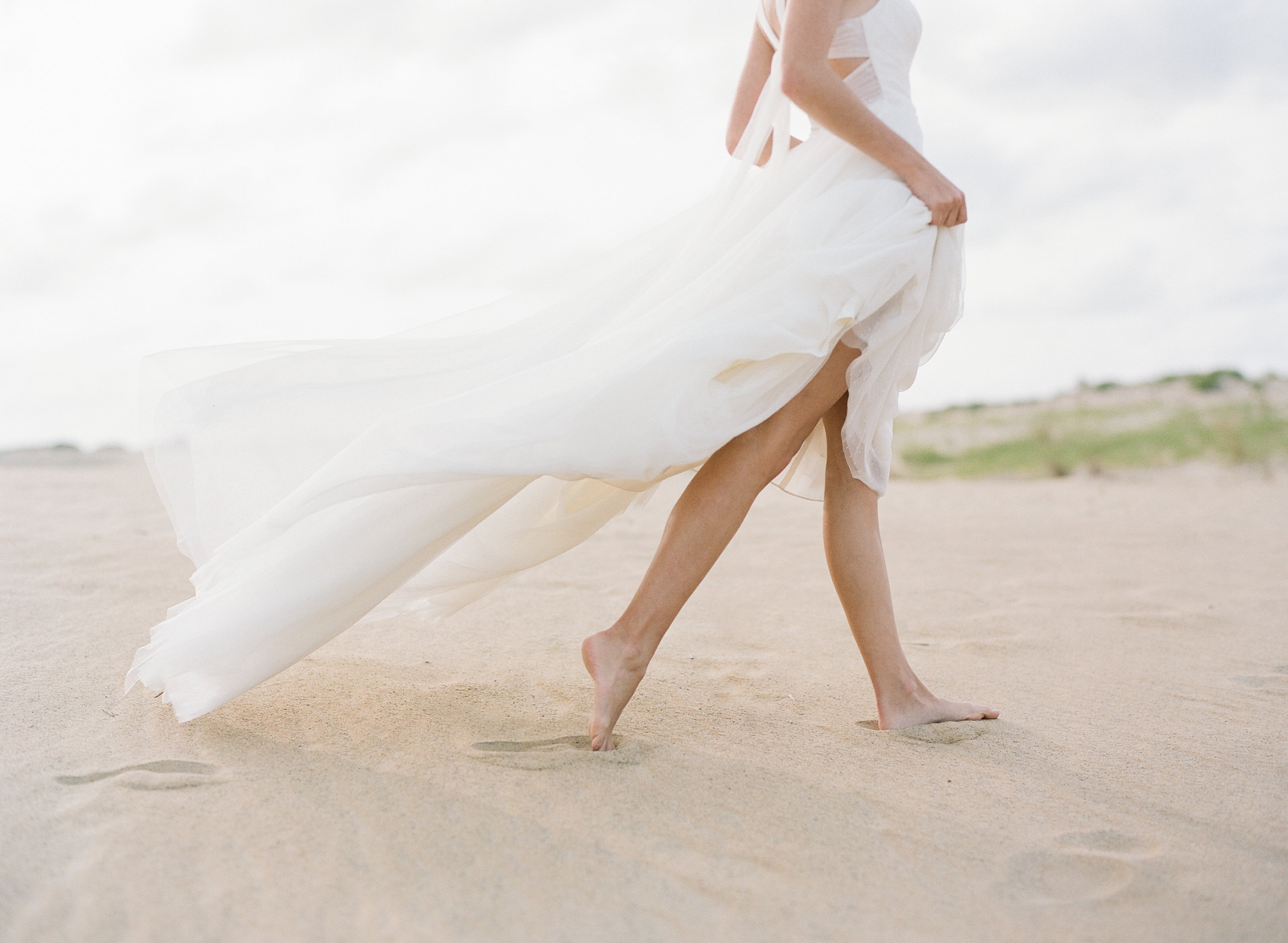Photo of bride walking barefoot in flowy dress for beach wedding