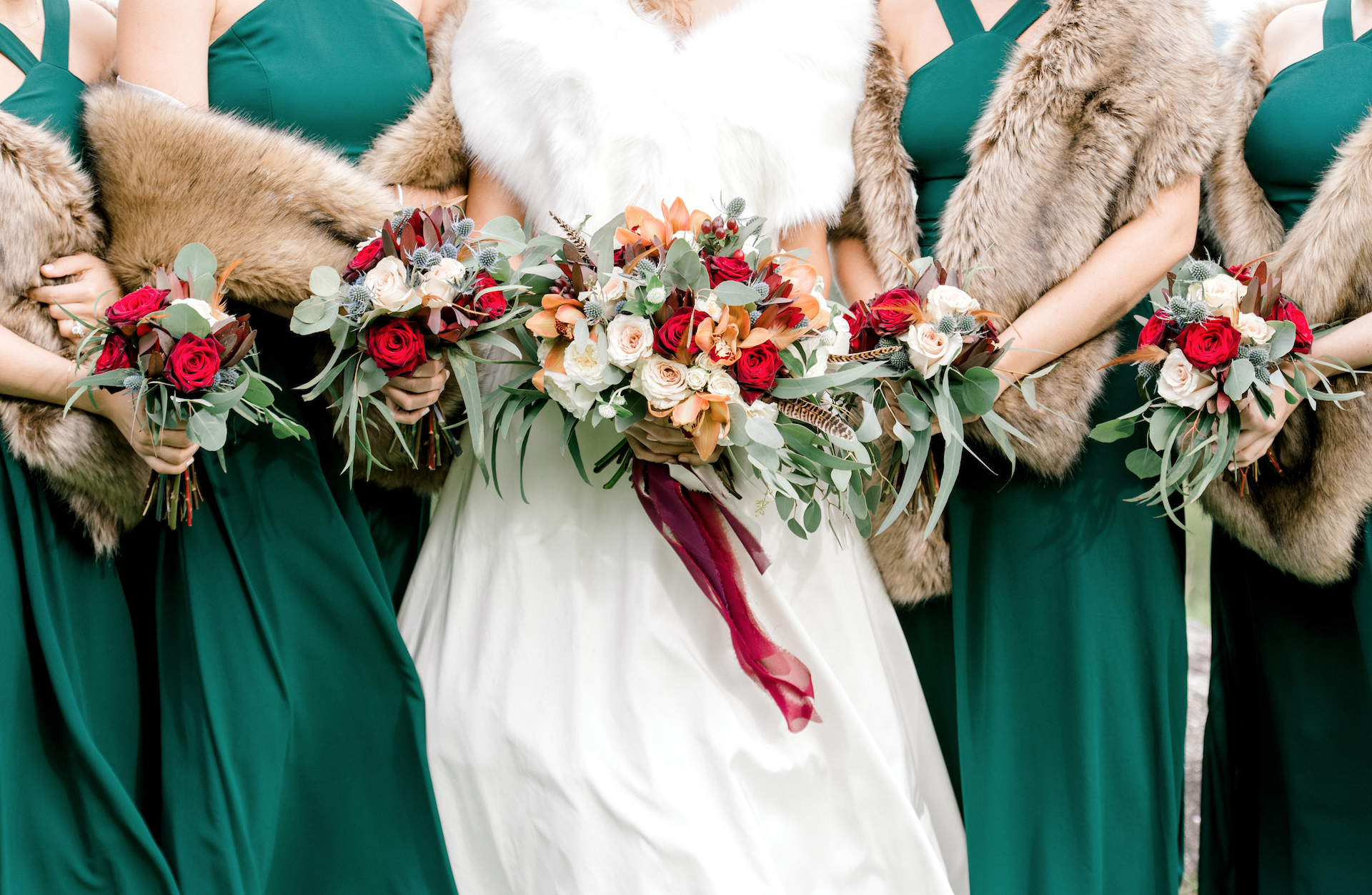 Bridesmaids and and bride holding fall wedding bouquets in emerald green dresses