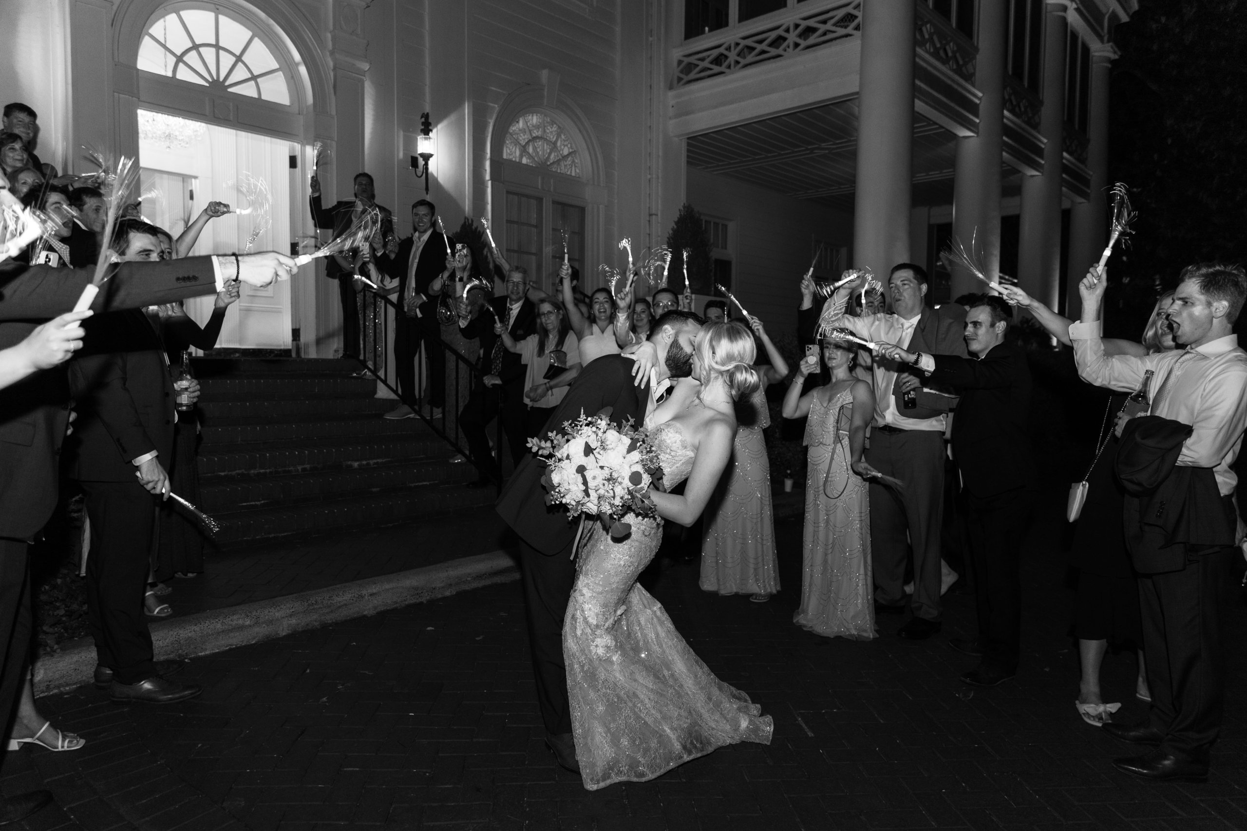 Black and white photo of couple kissing at grand send off for Duke Mansion wedding in North Carolina