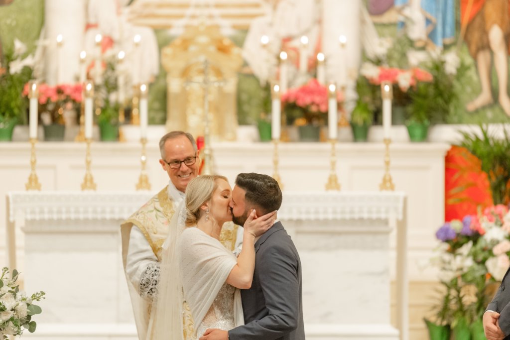 Bride and groom first kiss at Catholic wedding ceremony
